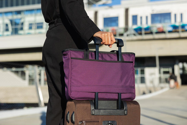 A Nomad attached to rolling luggage using the handle pass-through.